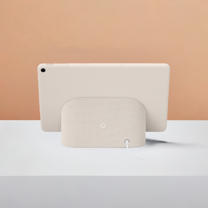 A white Google Nest Audio speaker is positioned in the foreground with a white Kosher Google Pixel Tablet - KosherOS 14 propped up behind it against a soft orange and pink gradient background.